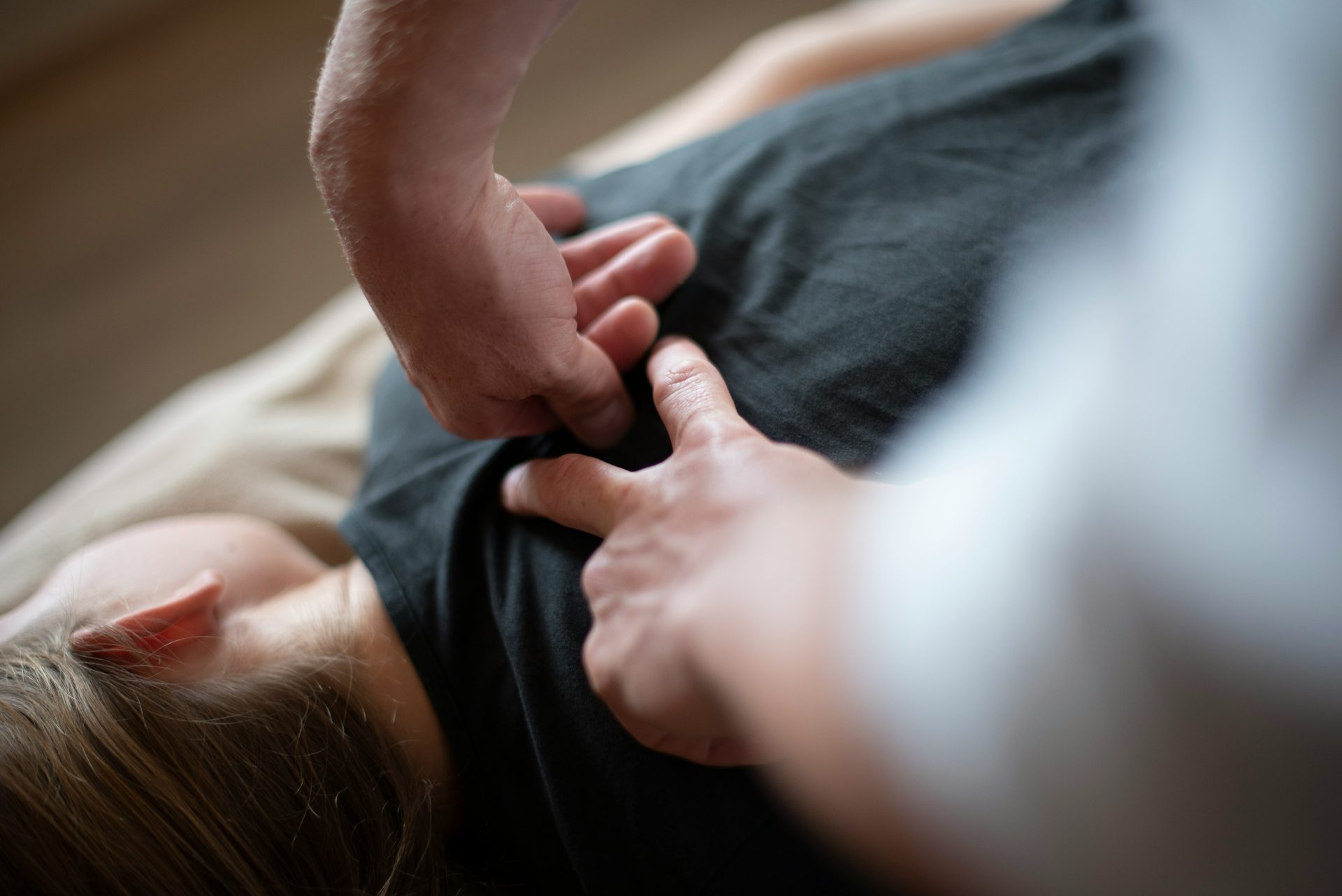 Una mujer acostada sobre una cama sosteniendo la mano de un hombre.