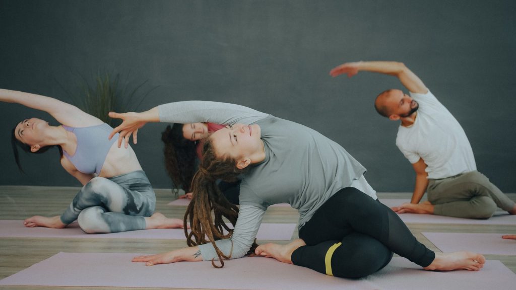 A diverse group of adults practicing yoga indoors, showcasing flexibility and mindfulness.